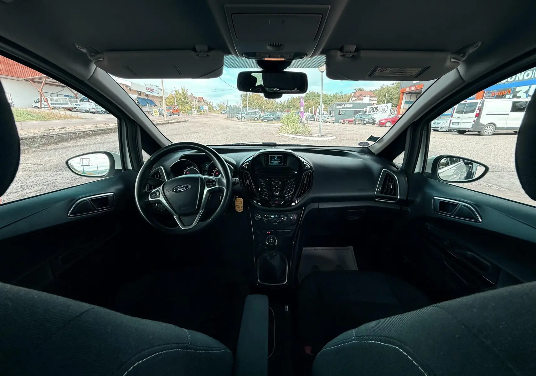 Vue intérieure avant du Ford B-MAX 2014, tableau de bord noir avec volant multifonction et levier de vitesse manuel.