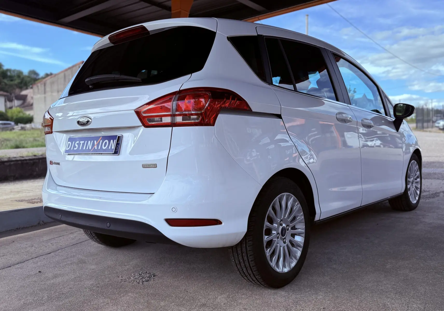 Vue 3/4 arrière droite d'une Ford B-MAX blanche, compacte avec vitres teintées et jantes alliage multibranches.