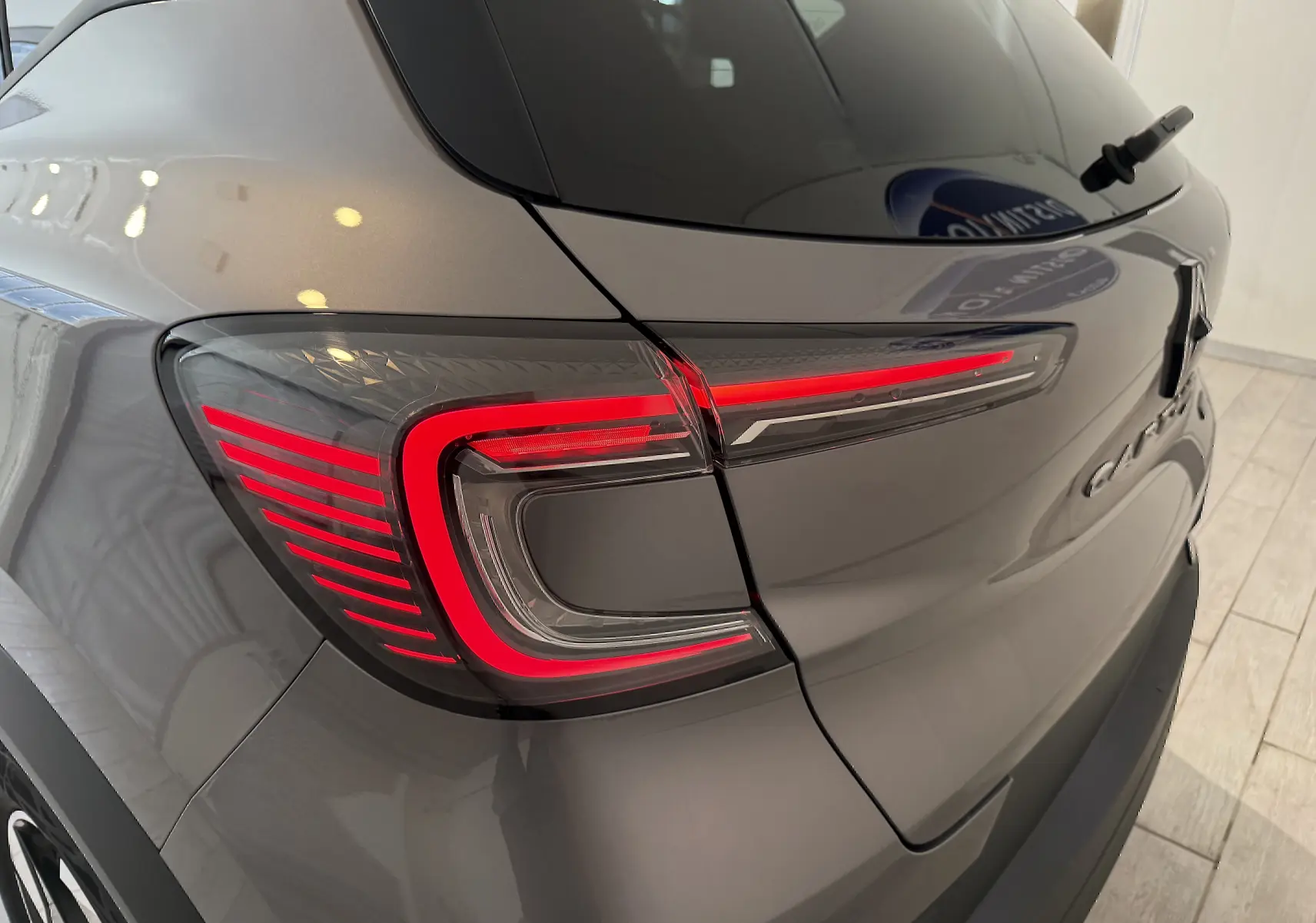 Gros plan sur le feu arrière gauche rouge vif du Renault Captur gris Cassiopée métal avec toit gris, vue arrière droite.