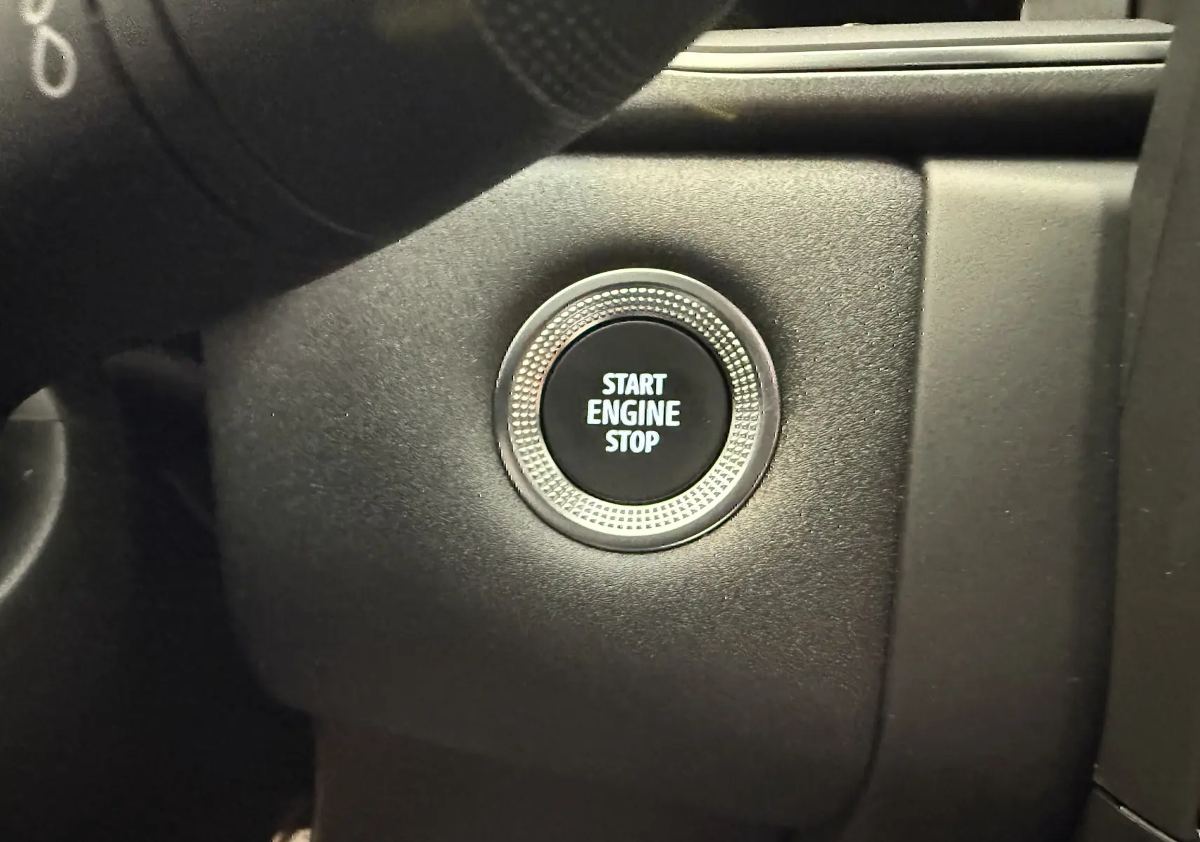 Bouton start/stop moteur en gros plan sur le tableau de bord noir du Renault Captur hybride 2025.