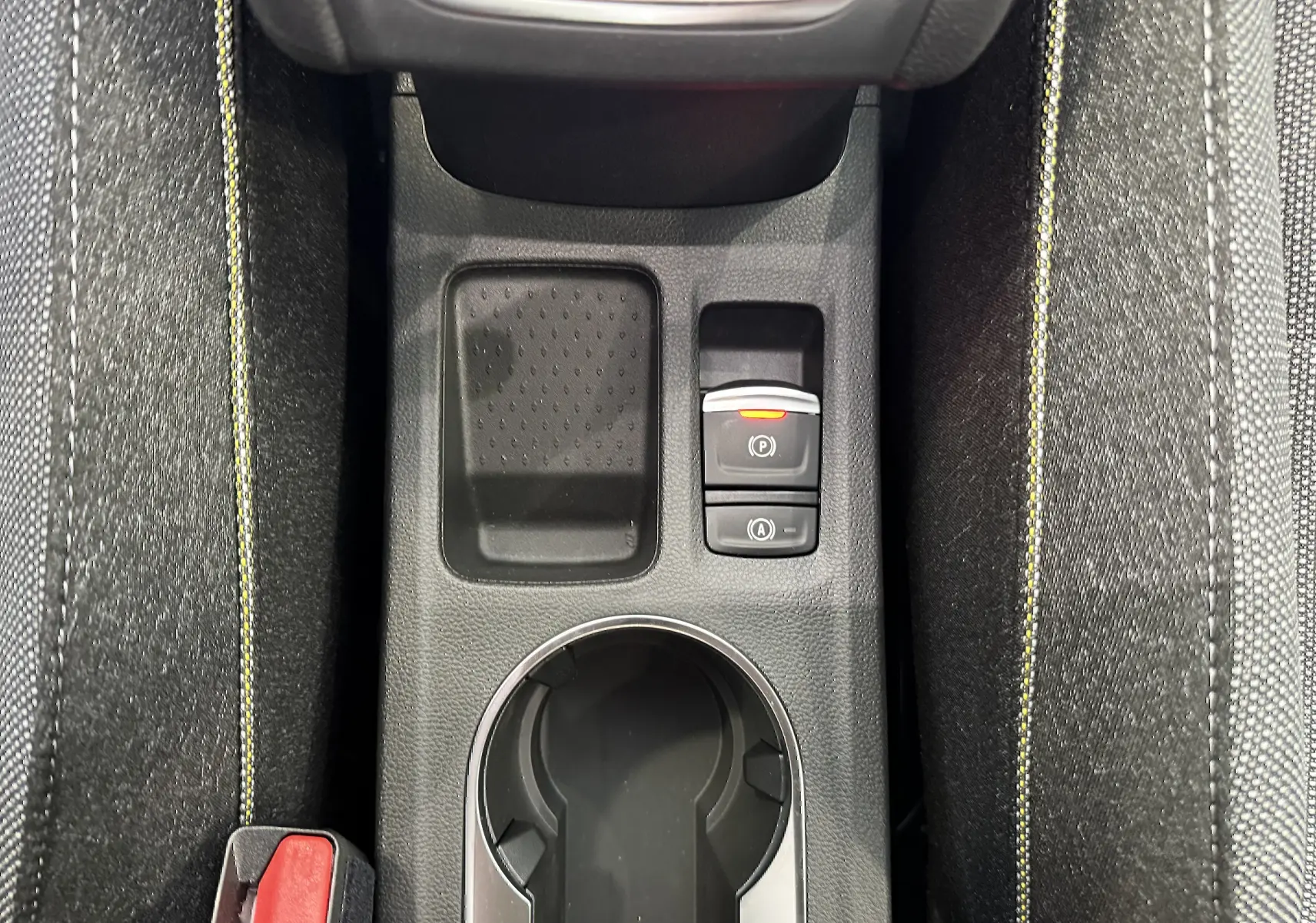 Vue rapprochée de la console centrale du Renault Captur 2025, avec surpiqûres jaunes et boutons de frein électronique.