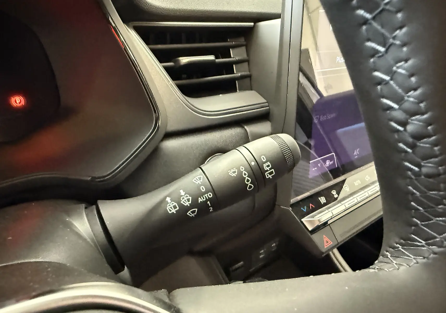 Gros plan sur la commande des essuie-glaces à gauche du volant dans l'habitacle gris du Renault Captur hybride 2025.