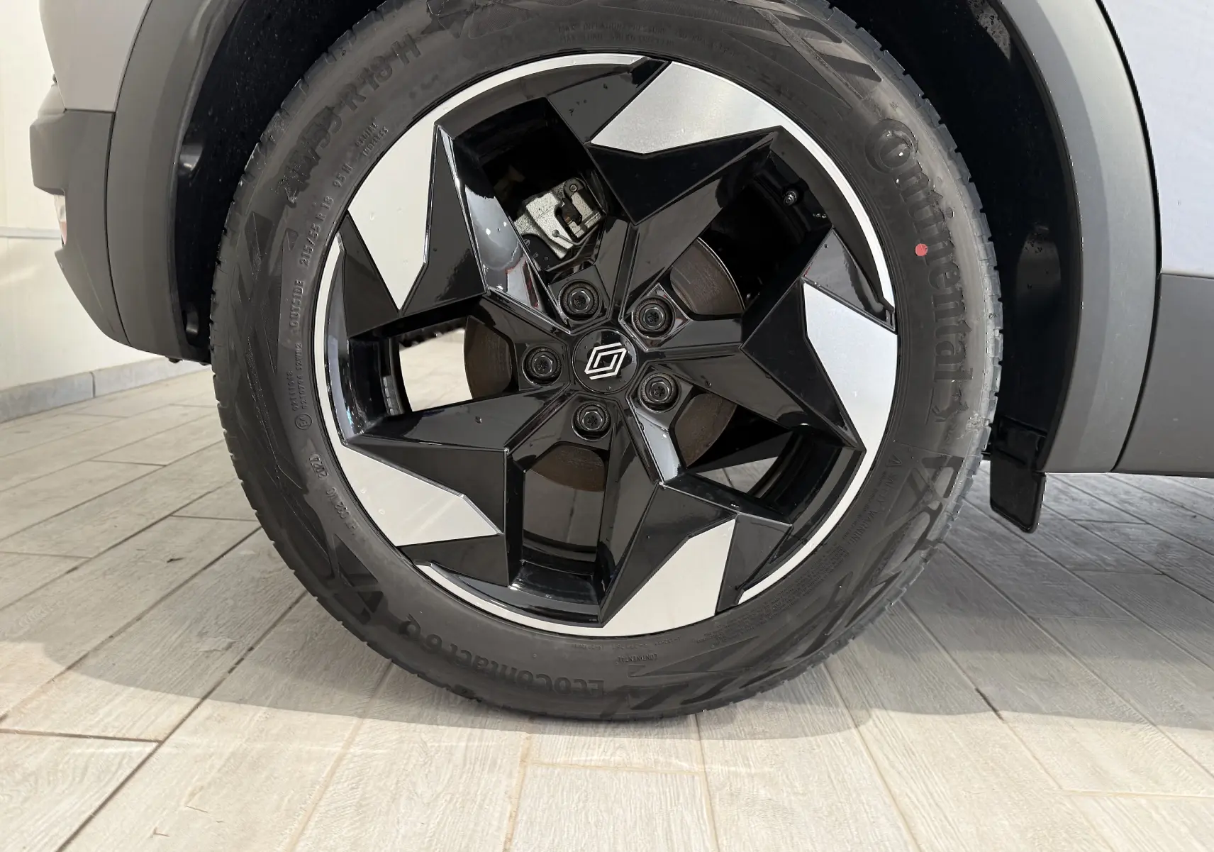 Gros plan sur la roue avant droite du Renault Captur gris Cassiopée, avec jante noire et argentée au design étoilé.