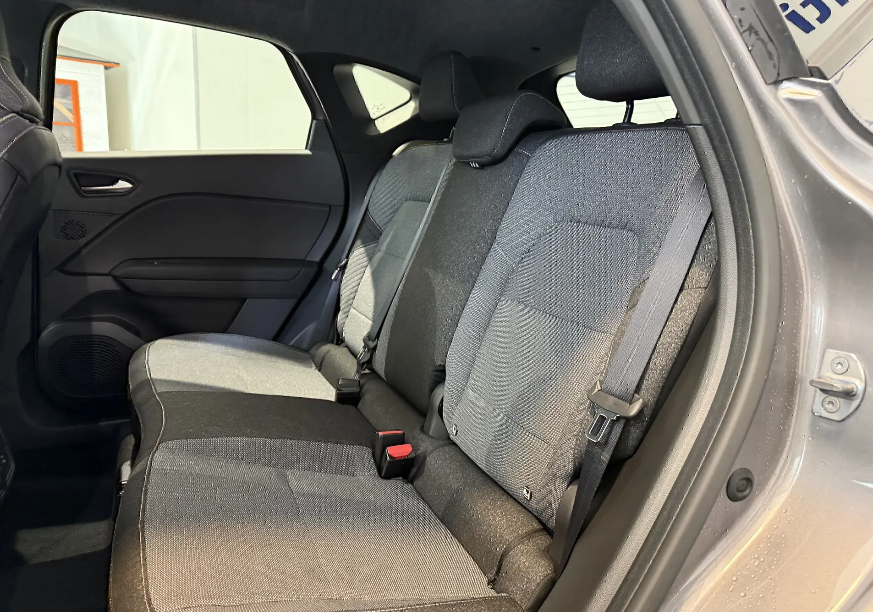 Vue intérieure côté droit des sièges arrière gris du Renault Captur 1.6 E-TECH Full Hybrid 2025 avec portière ouverte.