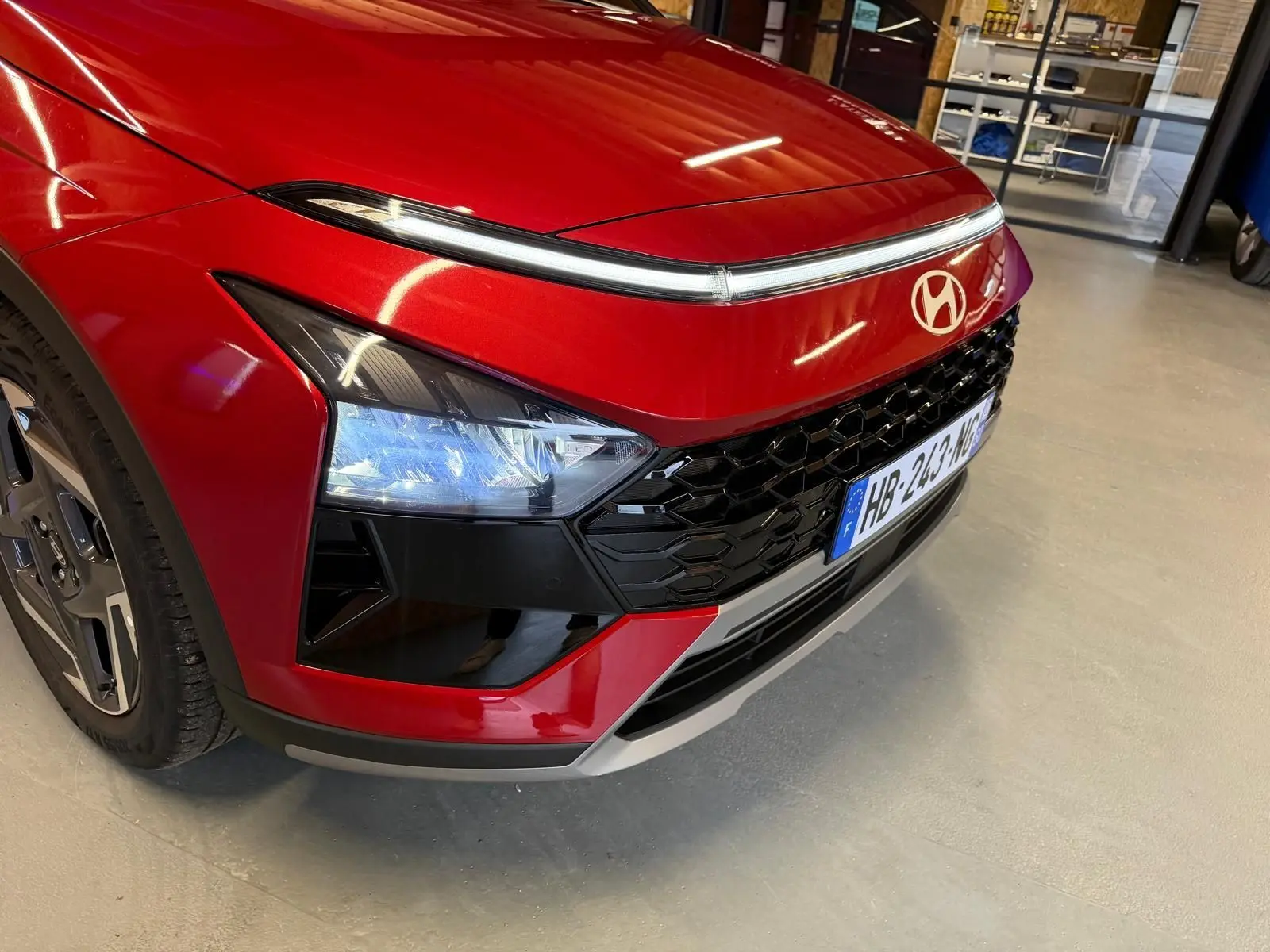 Gros plan sur l’avant droit du Hyundai Bayon rouge 2025 avec calandre noir laqué et feux LED distinctifs.