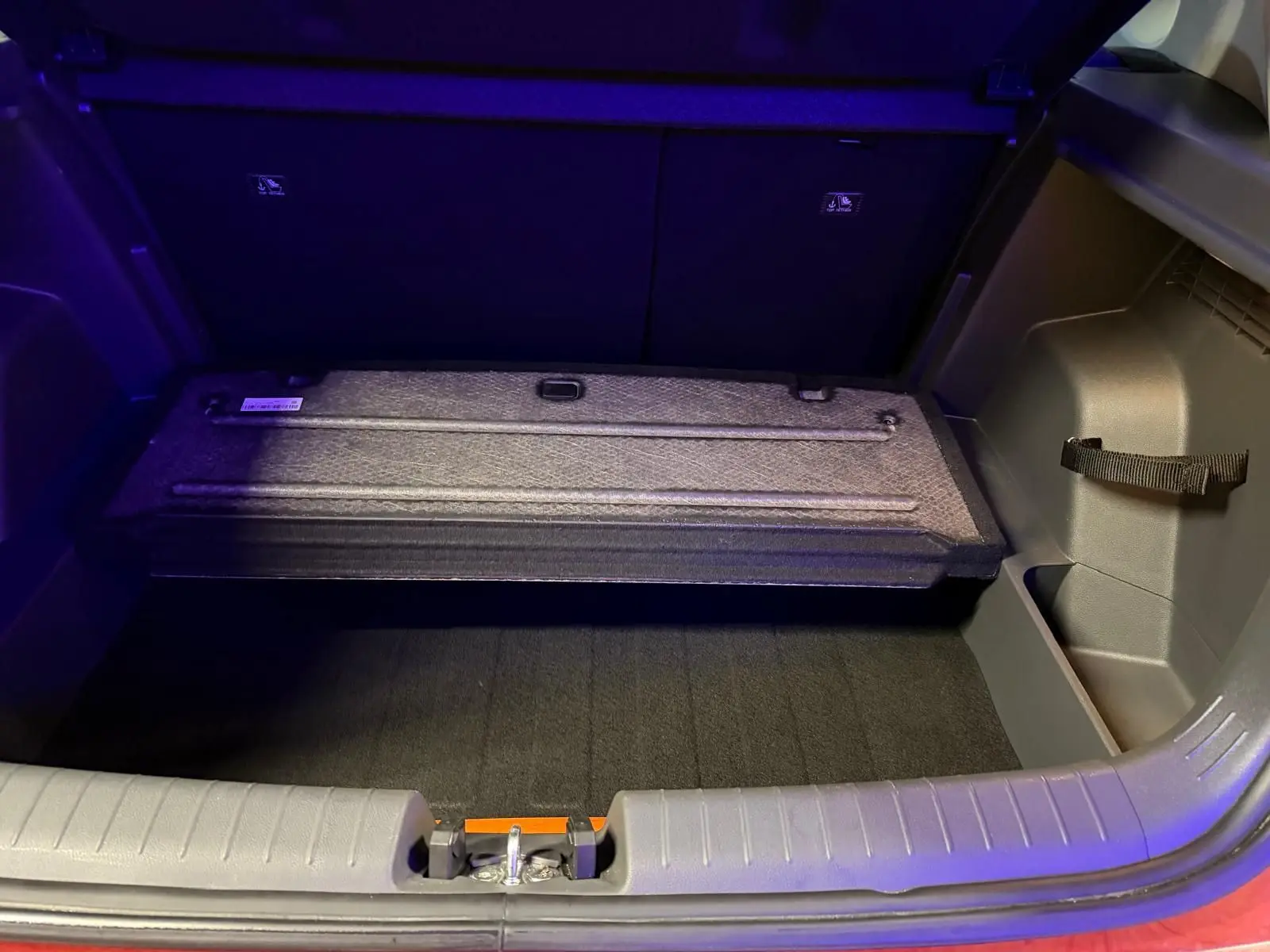 Coffre ouvert du Hyundai Bayon rouge 2025 montrant le compartiment de rangement sous plancher.