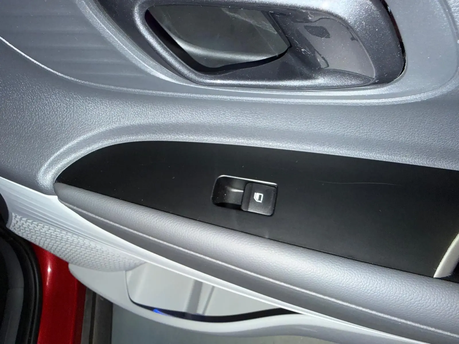 Détail de la commande de vitre côté gauche sur la porte intérieure d'une Hyundai Bayon rouge 2025.