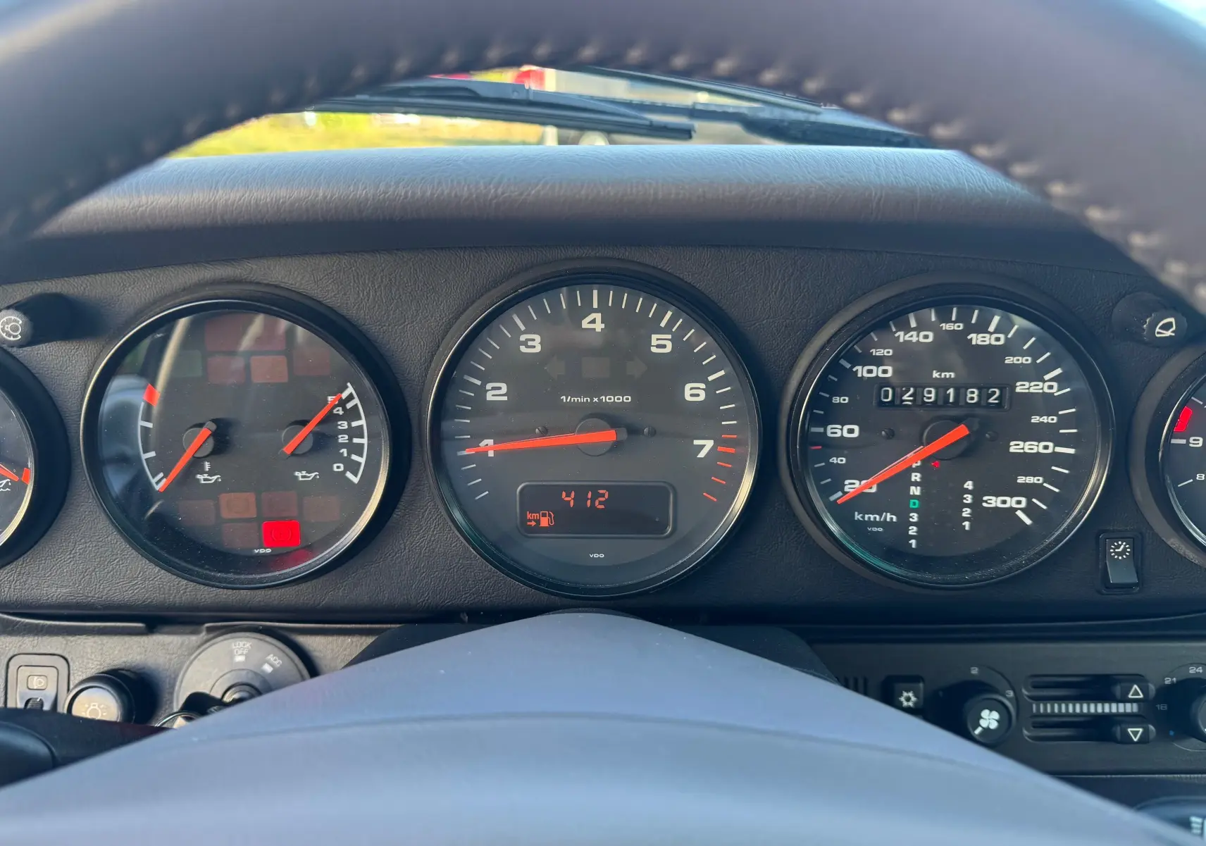 Vue rapprochée du tableau de bord et des compteurs noirs d'une Porsche 911 Carrera 2 gris polaire de 1996.