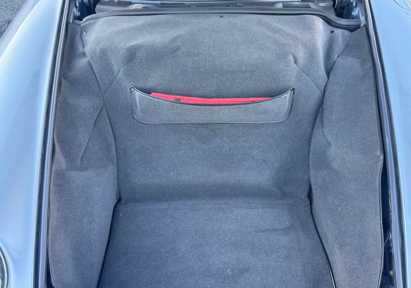 Vue plongeante sur le coffre avant gris polaire d'une Porsche 911 Carrera 993 de 1996, intérieur tissu gris avec pochette rouge.