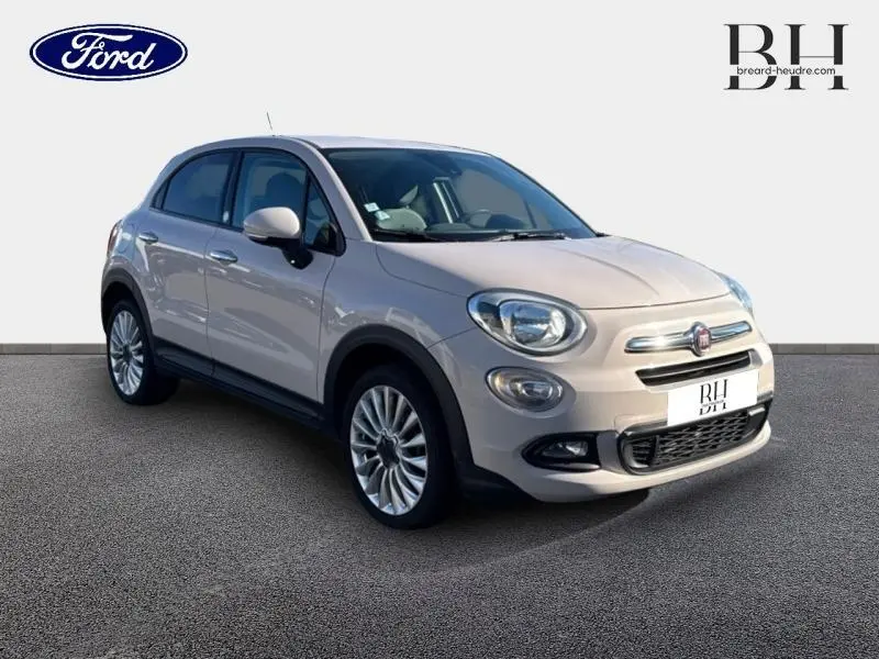 Vue 3/4 avant d'une FIAT 500X argentée avec jantes alu et boucliers couleur caisse sur fond neutre.