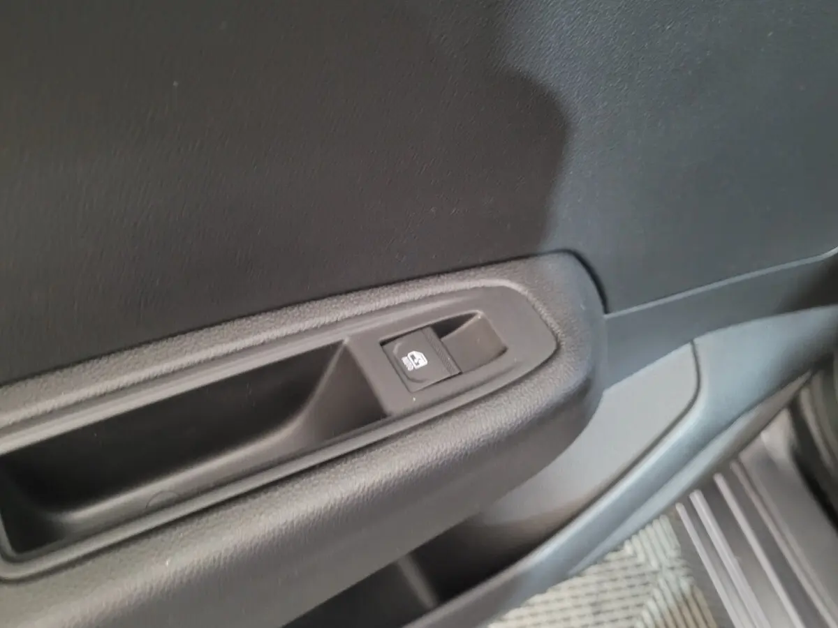 Détail de la commande de lève-vitre côté conducteur sur la porte intérieure d'une Renault Clio gris foncé.