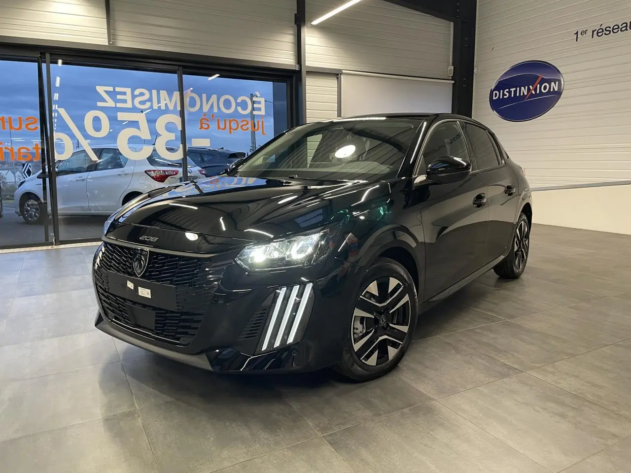 Peugeot 208 noir métallisé vue 3/4 avant droit avec feux LED et jantes alliage bi-tons en showroom.