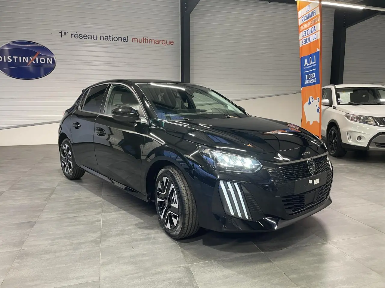 Peugeot 208 noir métallisé vue 3/4 avant avec feux LED et jantes alliage bi-tons en showroom.