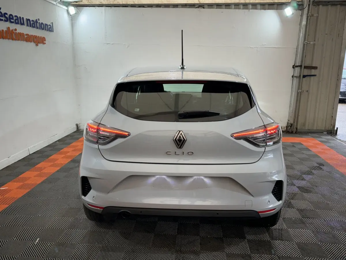 Vue arrière d'une Renault Clio gris clair 2025 avec feux LED allumés dans un garage.