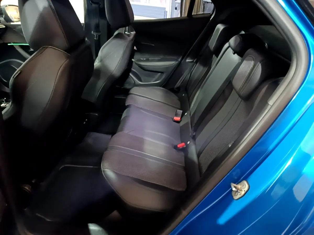 Vue intérieure côté droit sur la banquette arrière en cuir noir du Peugeot 2008 bleu, avec porte ouverte.