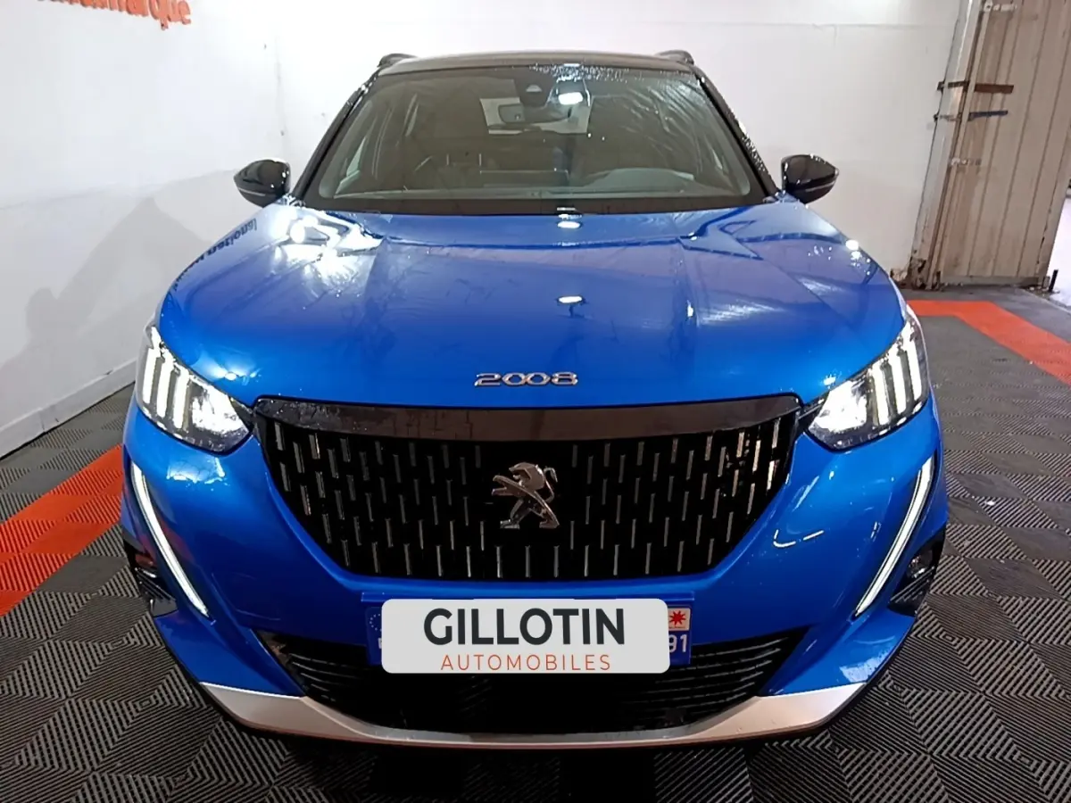 Vue avant d’un Peugeot 2008 bleu avec calandre noire et feux LED allumés dans un garage.