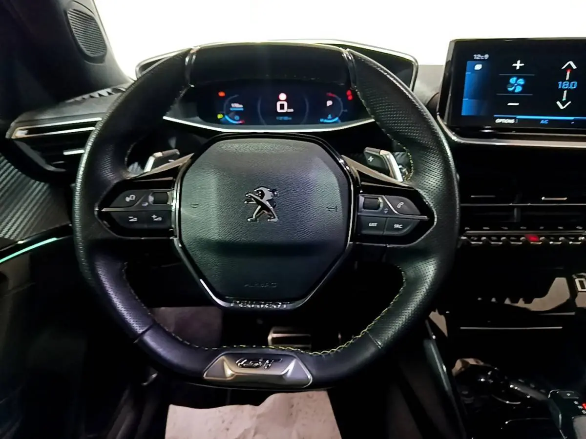 Vue rapprochée du volant cuir noir multifonctions et du tableau de bord numérique du Peugeot 2008 GT 2021.