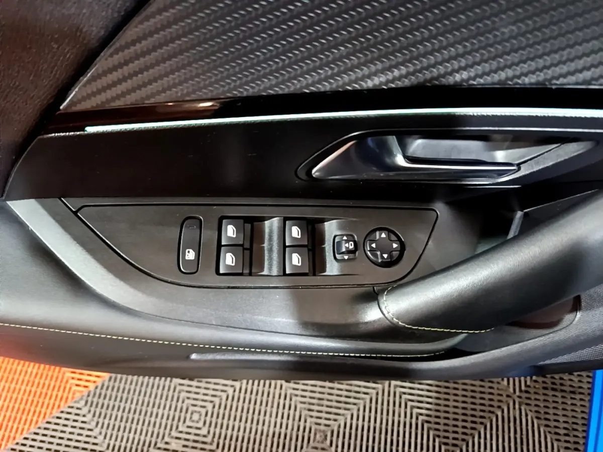 Gros plan sur la commande des vitres et rétroviseurs côté conducteur d’un Peugeot 2008 bleu, finition GT.