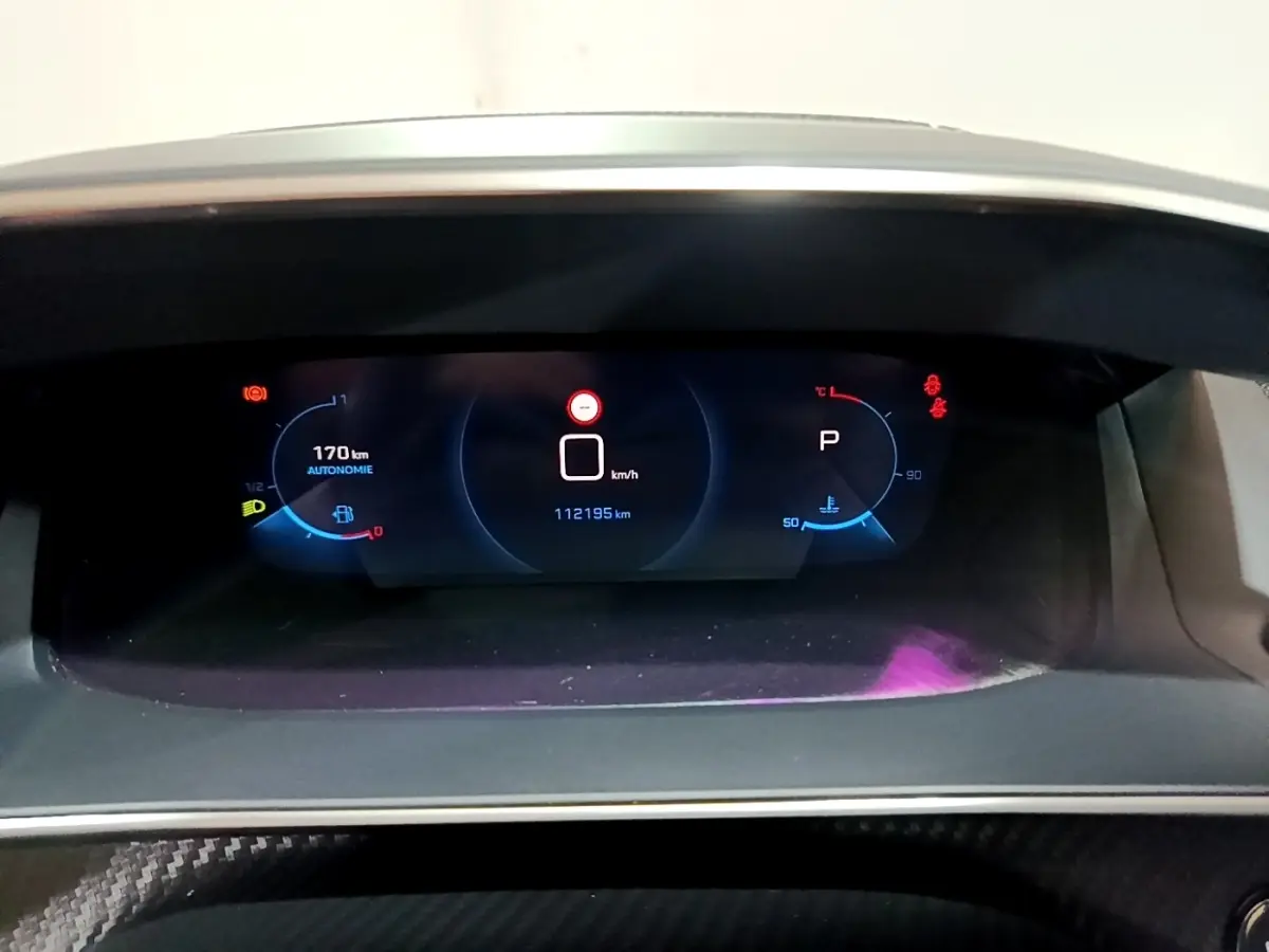 Vue rapprochée du tableau de bord numérique du Peugeot 2008 Bleu, affichant l'autonomie et la vitesse à l'arrêt.