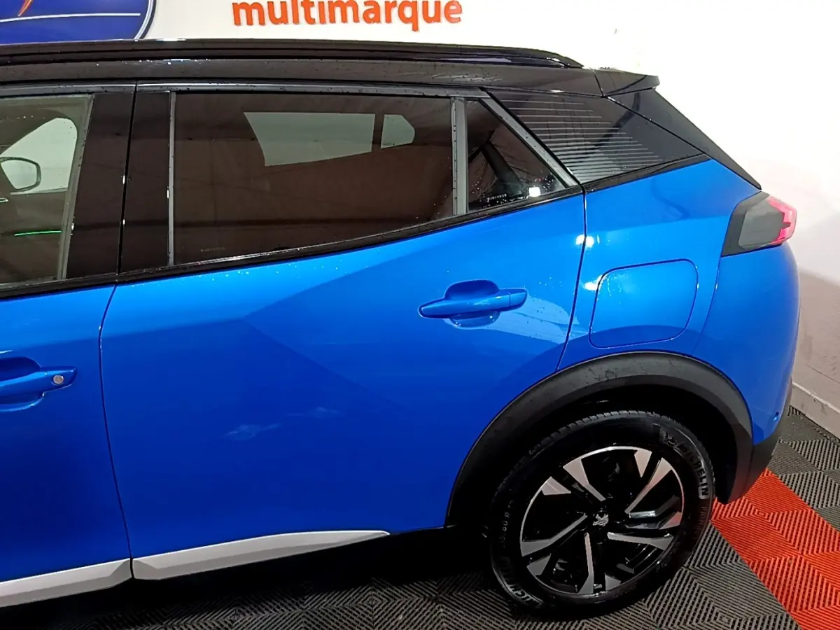 Vue latérale côté droit du Peugeot 2008 Bleu avec jantes noires et toit noir contrasté, arrière partiel visible.
