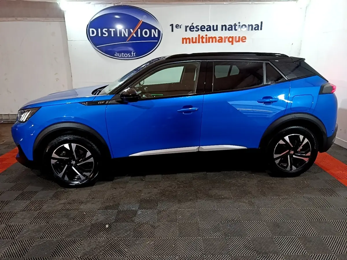 Vue de profil côté gauche d’un Peugeot 2008 Bleu GT 2021 avec toit noir et jantes alliage noires.