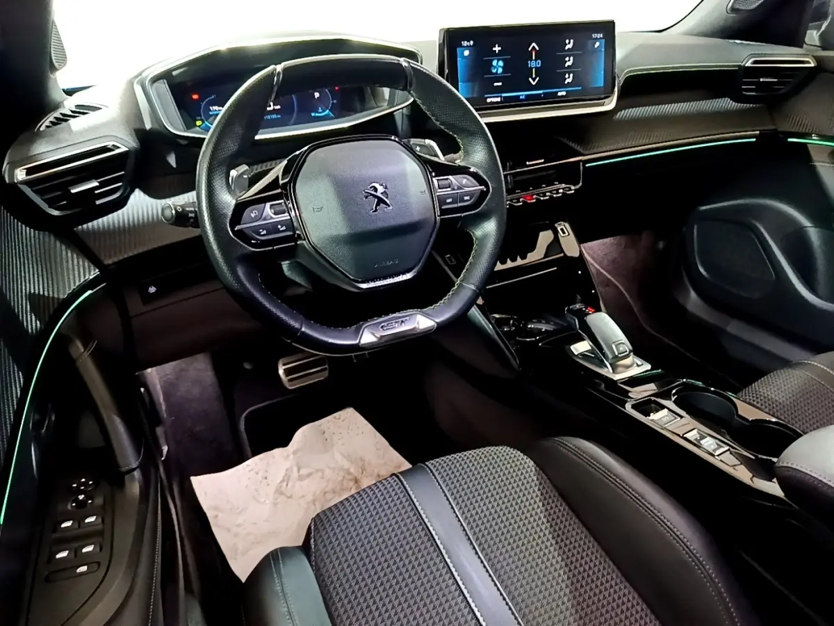 Vue intérieure côté conducteur du Peugeot 2008 Bleu, avec volant cuir compact, écran tactile 10 pouces et éclairage d'ambiance vert.