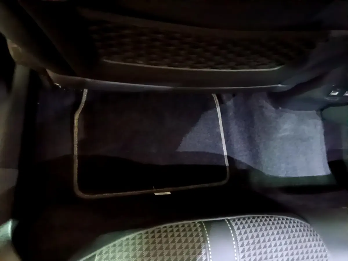 Vue intérieure du plancher côté passager arrière du Peugeot 2008 GT avec tapis de sol noir et siège tissu noir à motifs.
