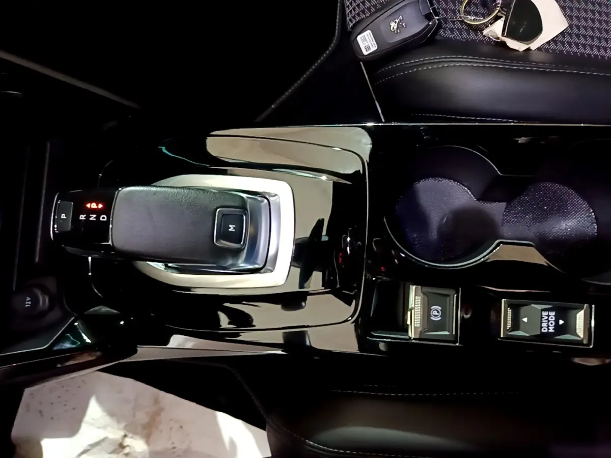 Vue plongeante sur la console centrale noire brillante du Peugeot 2008 GT avec levier de vitesse automatique et commandes Drive Mode.