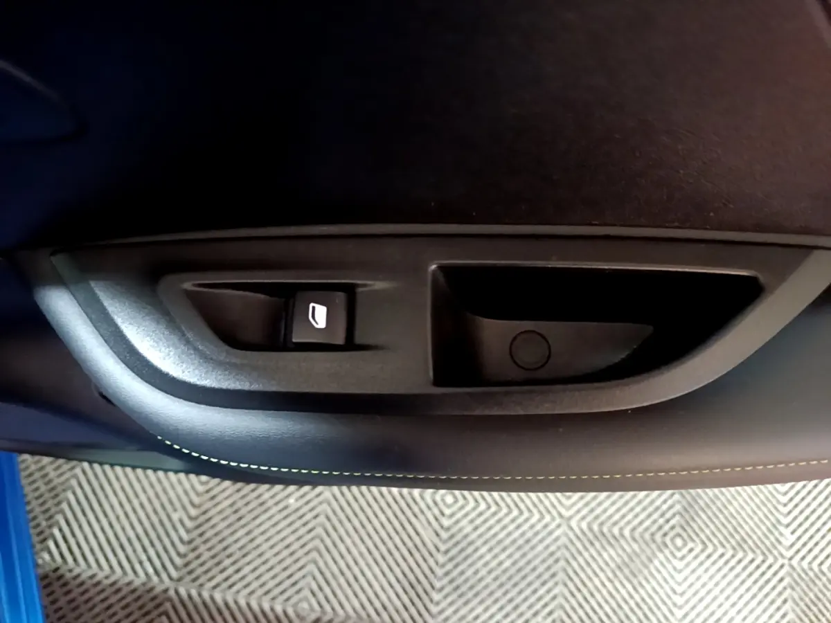 Gros plan sur la commande de lève-vitre côté gauche d’une Peugeot 2008 Bleu GT 2021, intérieur noir.