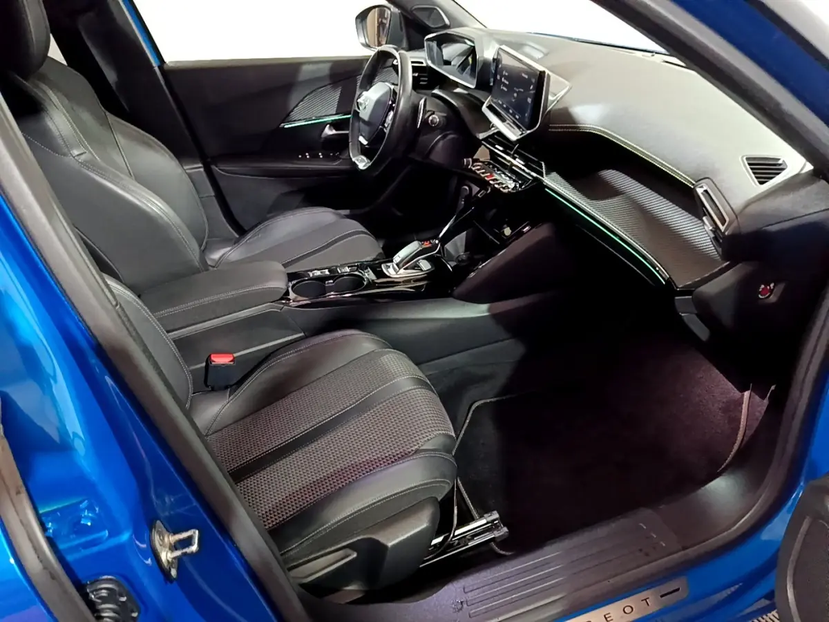 Vue intérieure côté conducteur du Peugeot 2008 bleu 2021, avec tableau de bord numérique et sièges en cuir noirs.