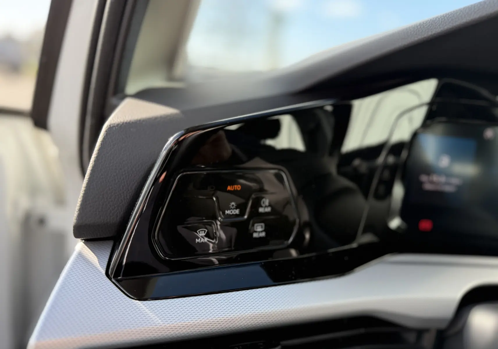 Détail du tableau de bord noir brillant côté gauche avec commandes de climatisation sur Volkswagen Golf blanche 2020.