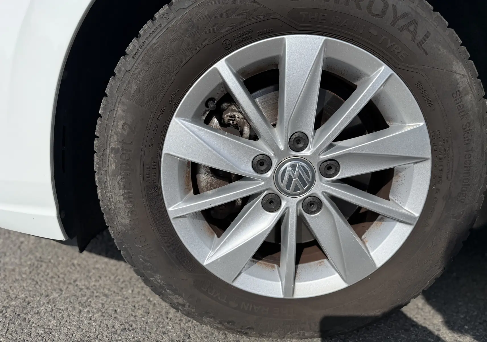 Gros plan sur la roue avant gauche d’une Volkswagen Golf blanche 1.0 TSI 110 LIFE avec jante argentée et pneu Uniroyal.