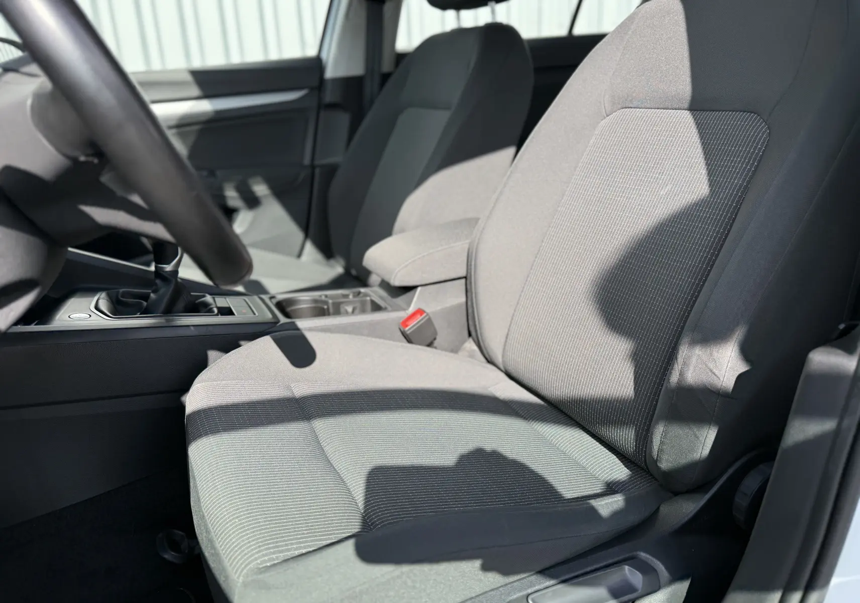 Gros plan sur les sièges avant en tissu gris de la Volkswagen Golf 1.0 TSI 110 LIFE, avec levier de vitesses manuel visible.