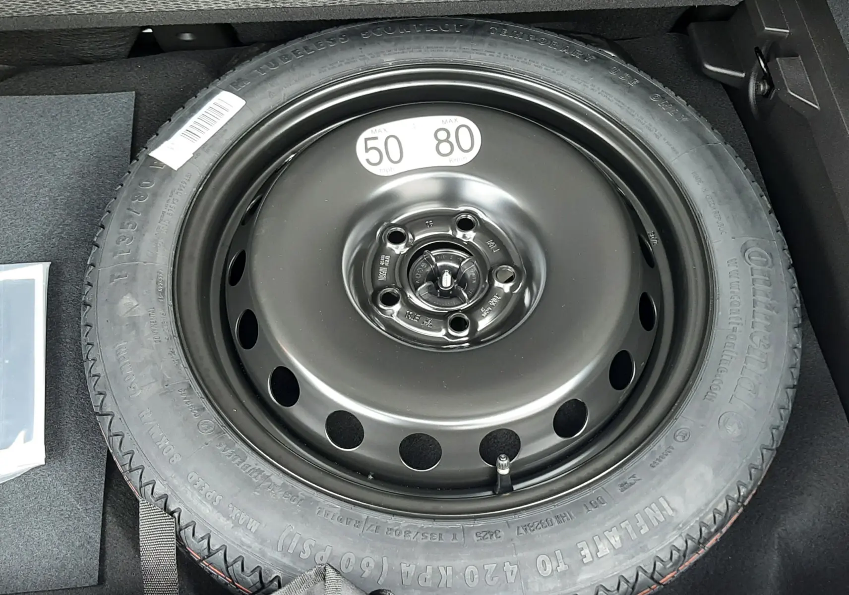 Pneu de secours noir dans le coffre d’un Renault Captur E-Tech Full Hybrid 160ch, sous la banquette arrière.