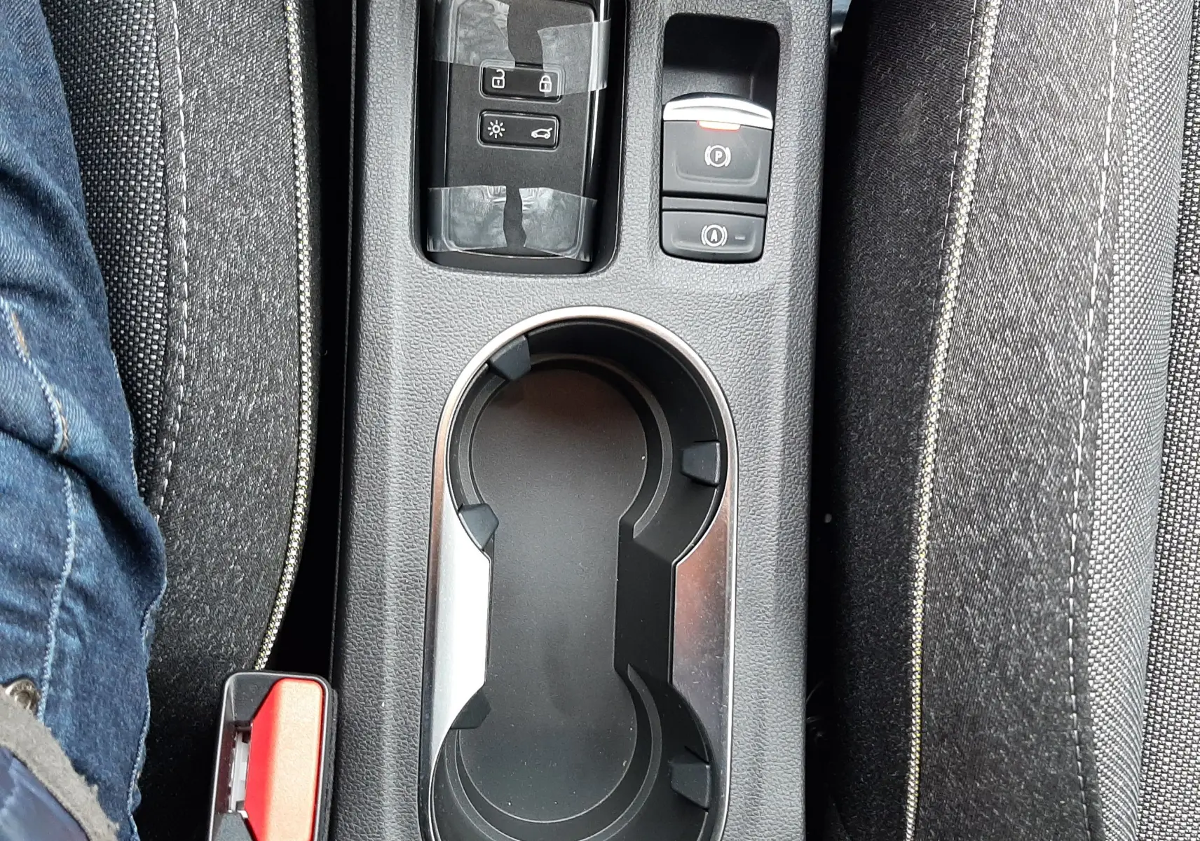 Vue plongeante sur la console centrale du Renault Captur E-Tech gris cassiopée, avec porte-gobelets et commandes électroniques.