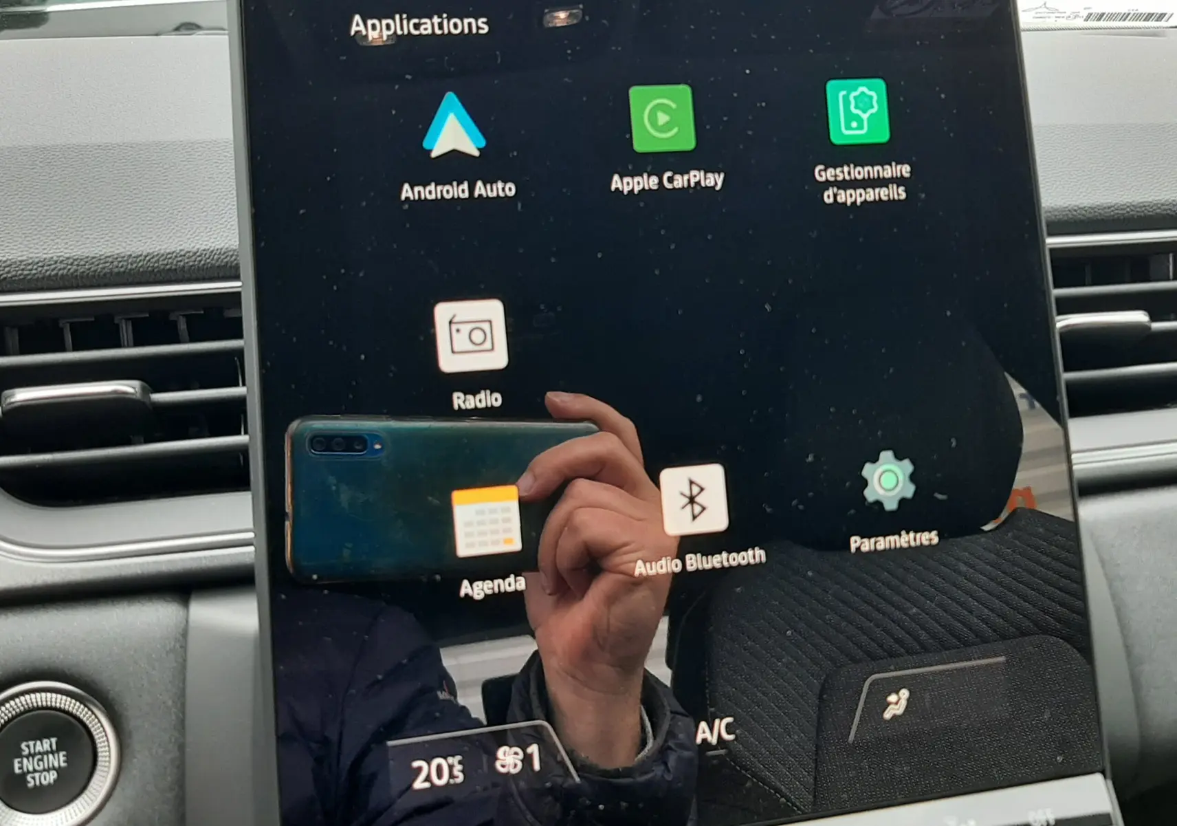 Écran tactile central du Renault Captur E-Tech 2026, affichant les applications connectées, avec tableau de bord gris en arrière-plan.
