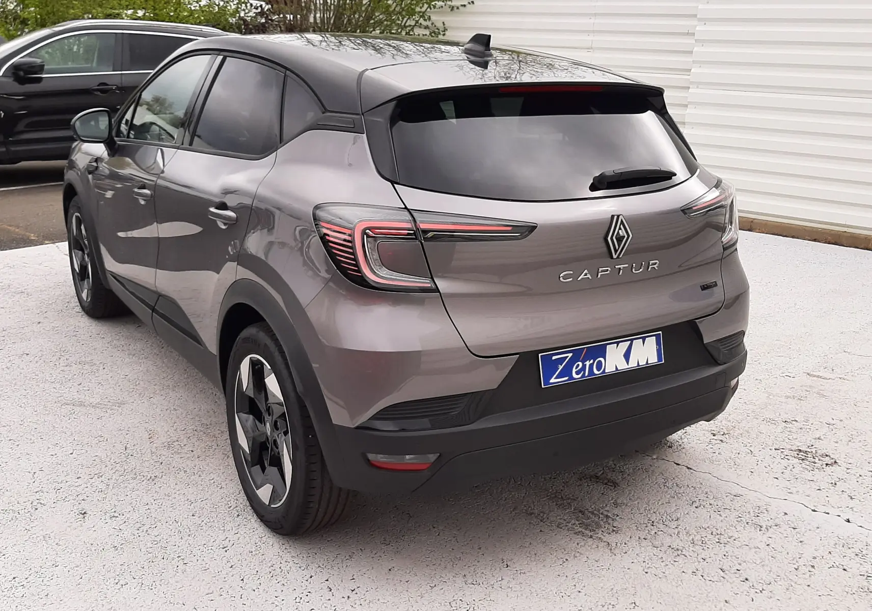 Vue 3/4 arrière droite du Renault Captur E-Tech gris Cassiopée avec toit noir et feux arrière LED distinctifs.