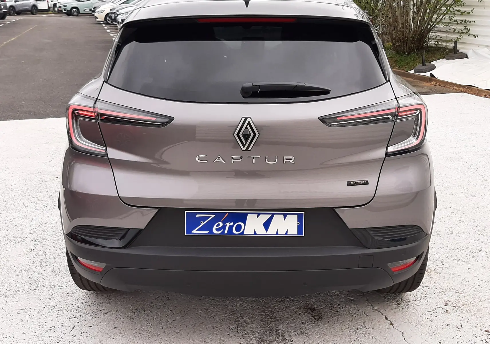 Vue arrière d'un Renault Captur E-Tech Full Hybrid gris Cassiopée avec toit noir, feux LED et plaque d'immatriculation Zero KM.