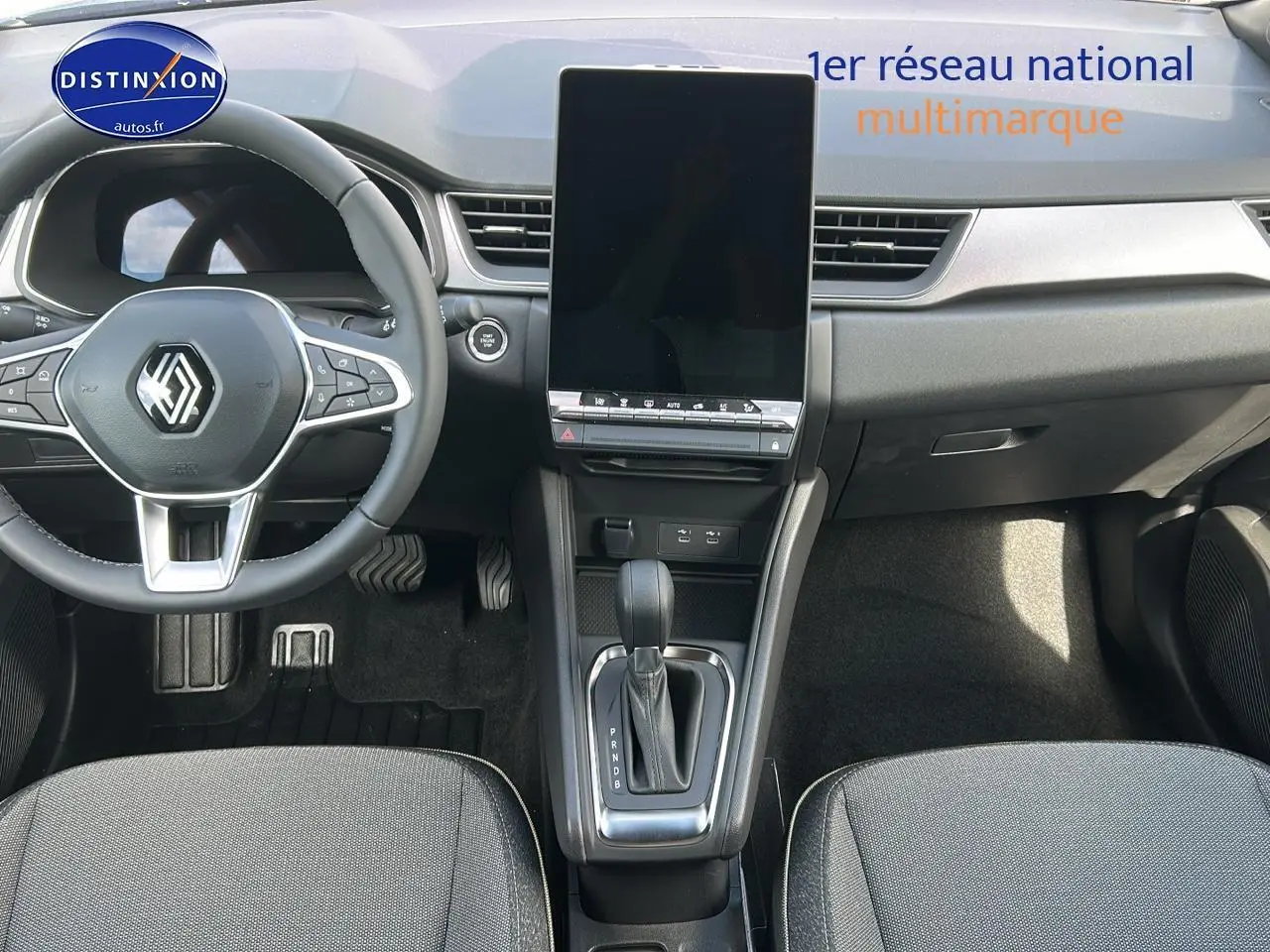 Vue intérieure avant du Renault Captur 2025 bleu iron, avec grand écran tactile vertical et volant multifonction.