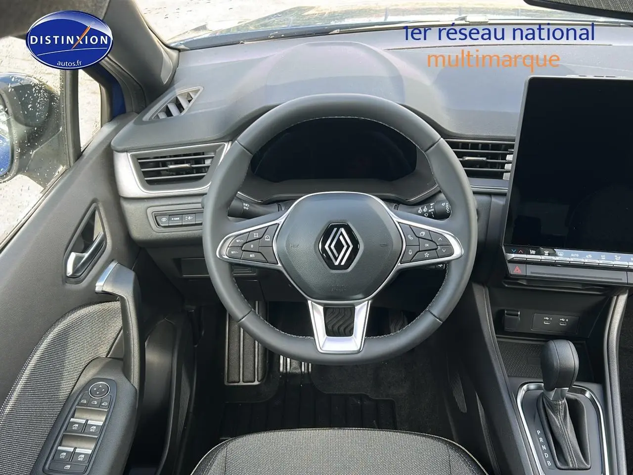 Vue intérieure centrée sur le volant multifonction et la console centrale du Renault Captur bleu iron 2025.