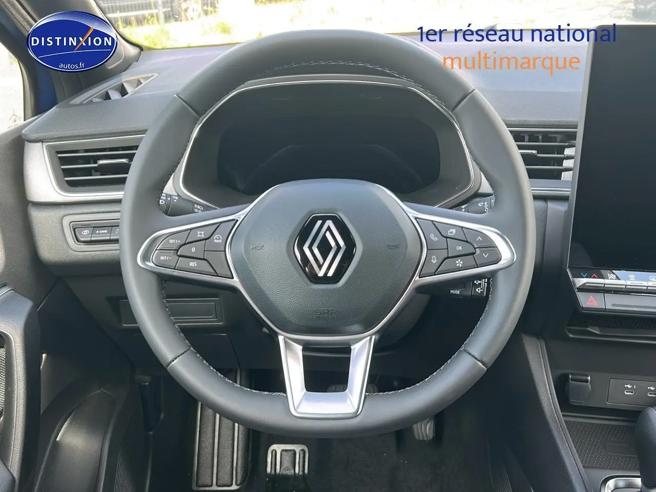 Vue intérieure centrée sur le volant multifonction noir du Renault Captur 2025, avec tableau de bord et écran tactile visibles.
