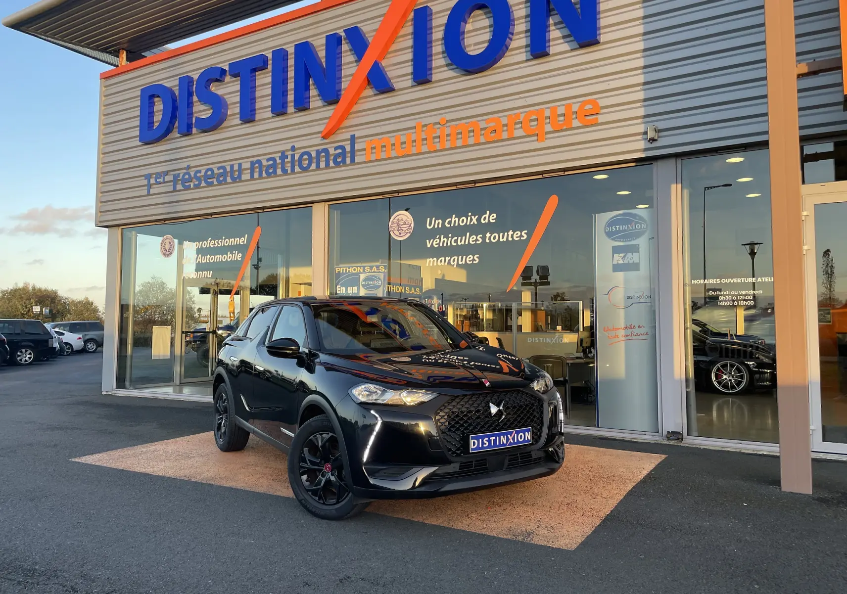 DS3 Crossback noir métal en 3/4 avant droit, avec calandre distinctive et jantes noires devant un showroom Distinxion.