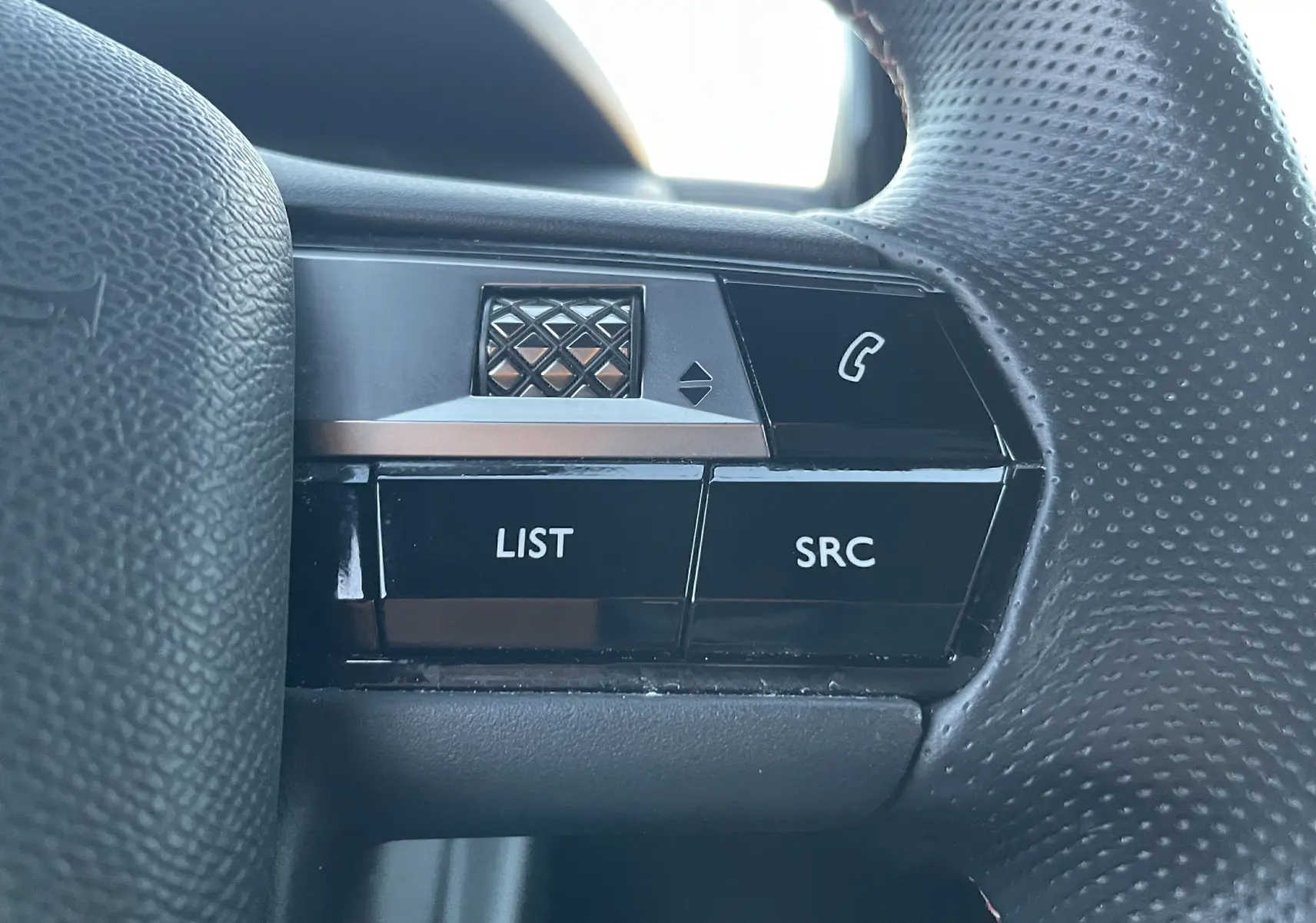 Gros plan sur les commandes gauche du volant noir perforé du DS3 Crossback 1.5 BlueHDi 130 Diesel 2021.