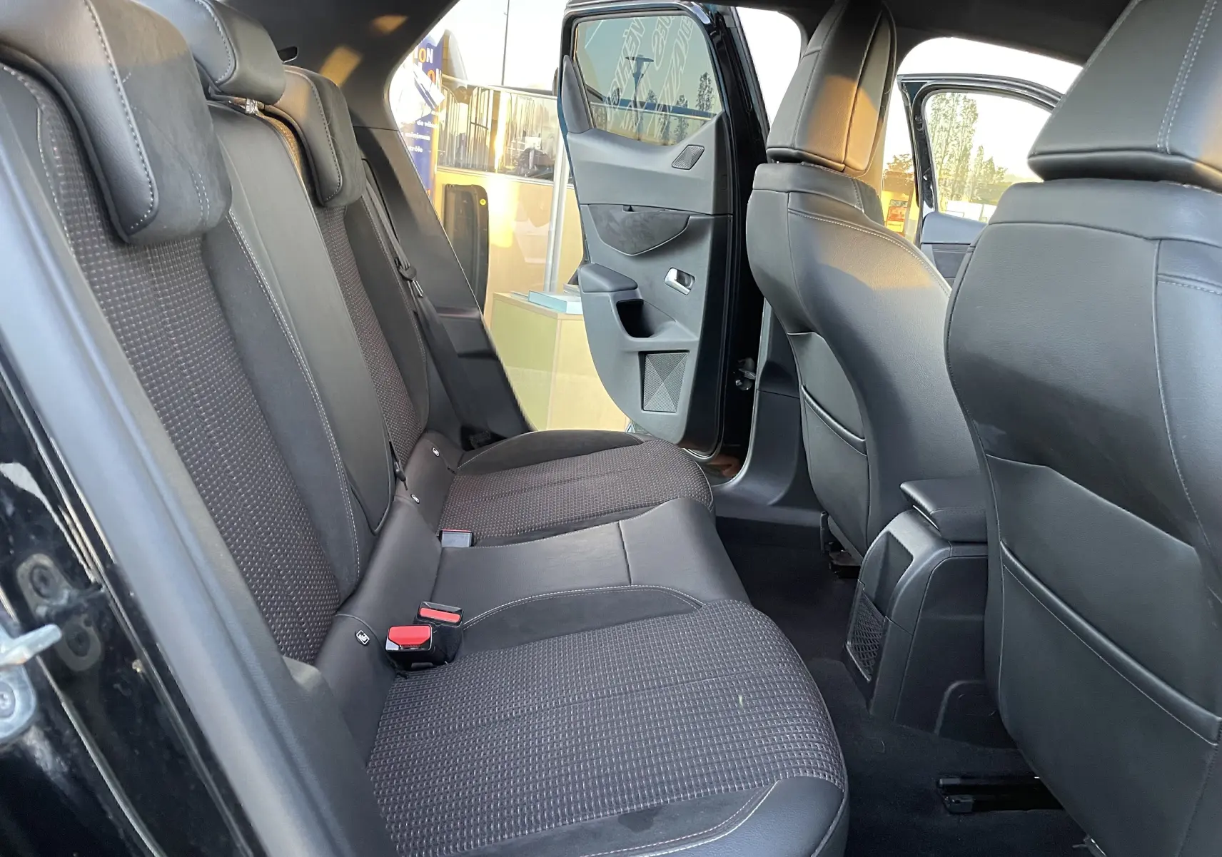 Vue intérieure arrière gauche du DS3 Crossback 2021 noir métal, sièges arrière en tissu et cuir noir avec porte ouverte.