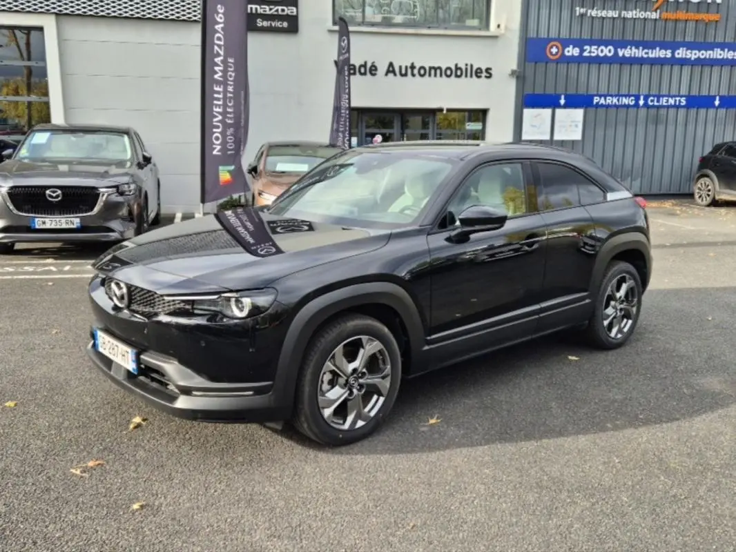 Vue 3/4 avant droite d'un Mazda MX-30 électrique noir, avec jantes alliage et sellerie Modern Confidence visible à travers les vitres.
