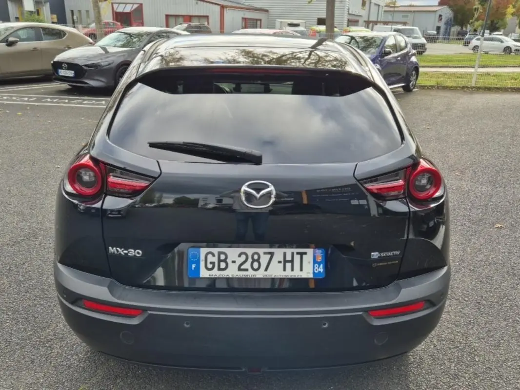 Vue arrière d'une Mazda MX-30 électrique noire de 2021 avec feux ronds et plaques d'immatriculation françaises.