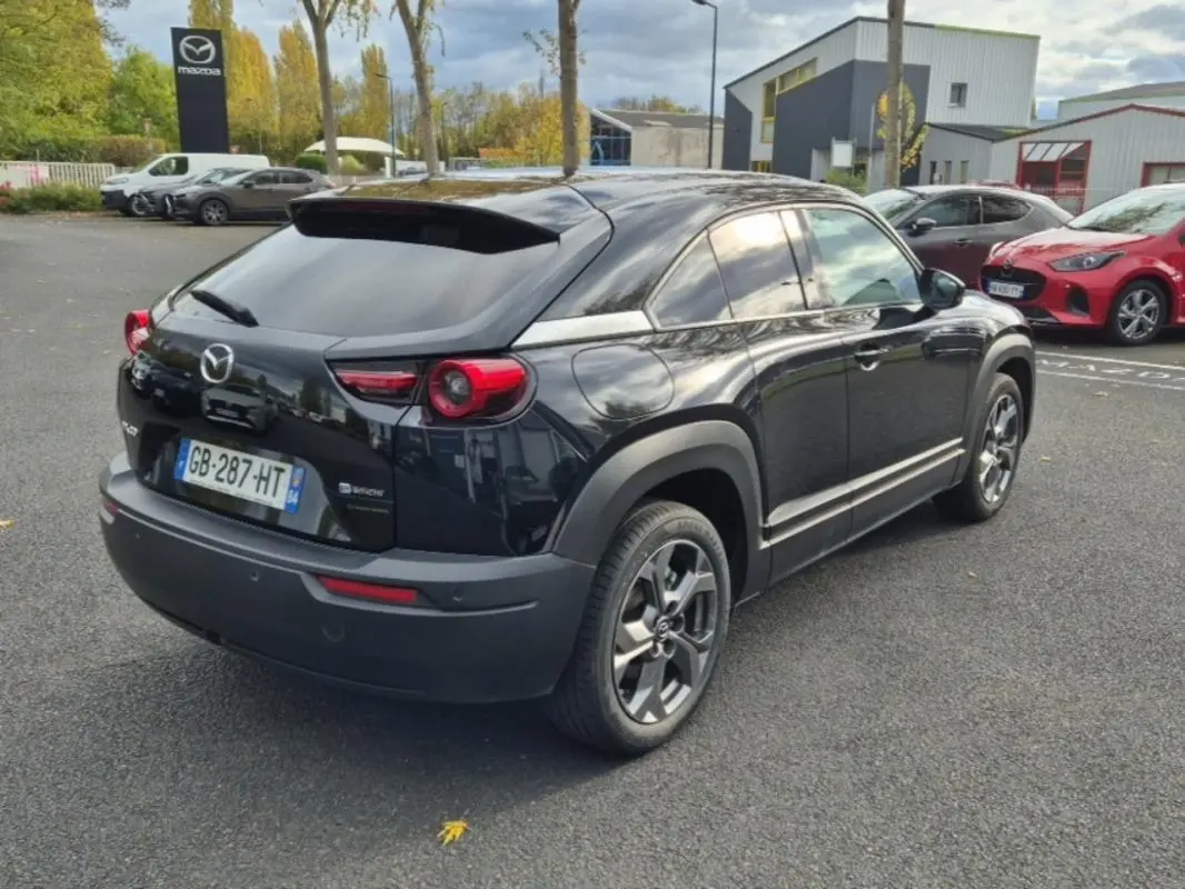 Vue 3/4 arrière droite d'un Mazda MX-30 électrique noir 2021, avec jantes spécifiques et détails de sellerie Modern Confidence.