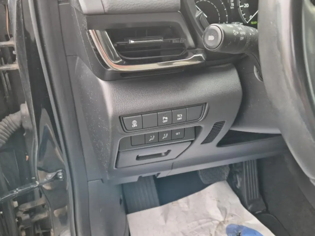 Vue rapprochée côté gauche du tableau de bord noir du Mazda MX-30 électrique, montrant les commandes de sécurité et ventilation.