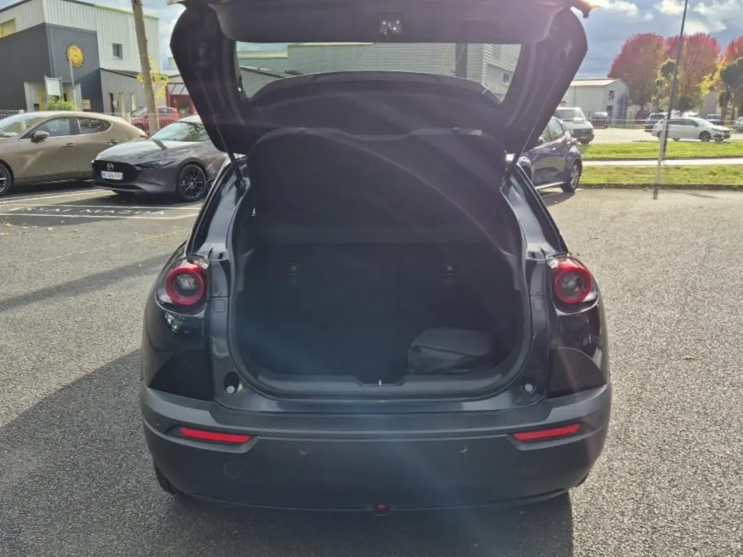 Vue arrière du Mazda MX-30 électrique noir 2021 avec coffre ouvert, soulignant ses feux ronds caractéristiques.