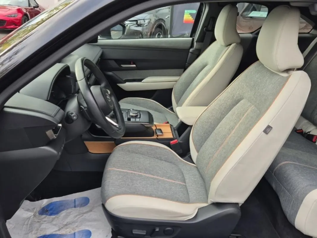 Intérieur du Mazda MX-30 First Edition 2021, vue côté conducteur sur les sièges gris et beige avec sellerie Modern Confidence.